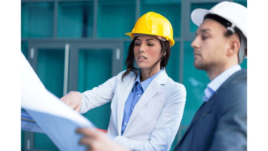 A woman in a hard hat and jacket holding papers.